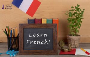Study desk with a chalkboard reading Learn French, French flag, books, pencils, and plant — representing tips to learn French faster before moving to Canada.