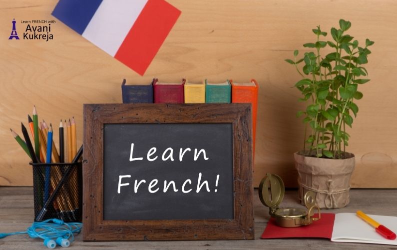 Study desk with a chalkboard reading Learn French, French flag, books, pencils, and plant — representing tips to learn French faster before moving to Canada.