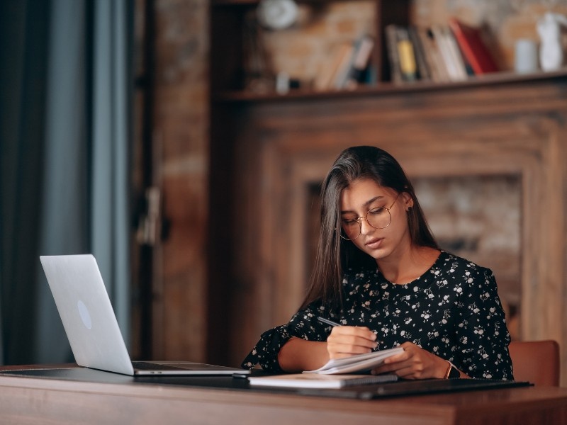 Student learning French independently at home using a laptop and study notes